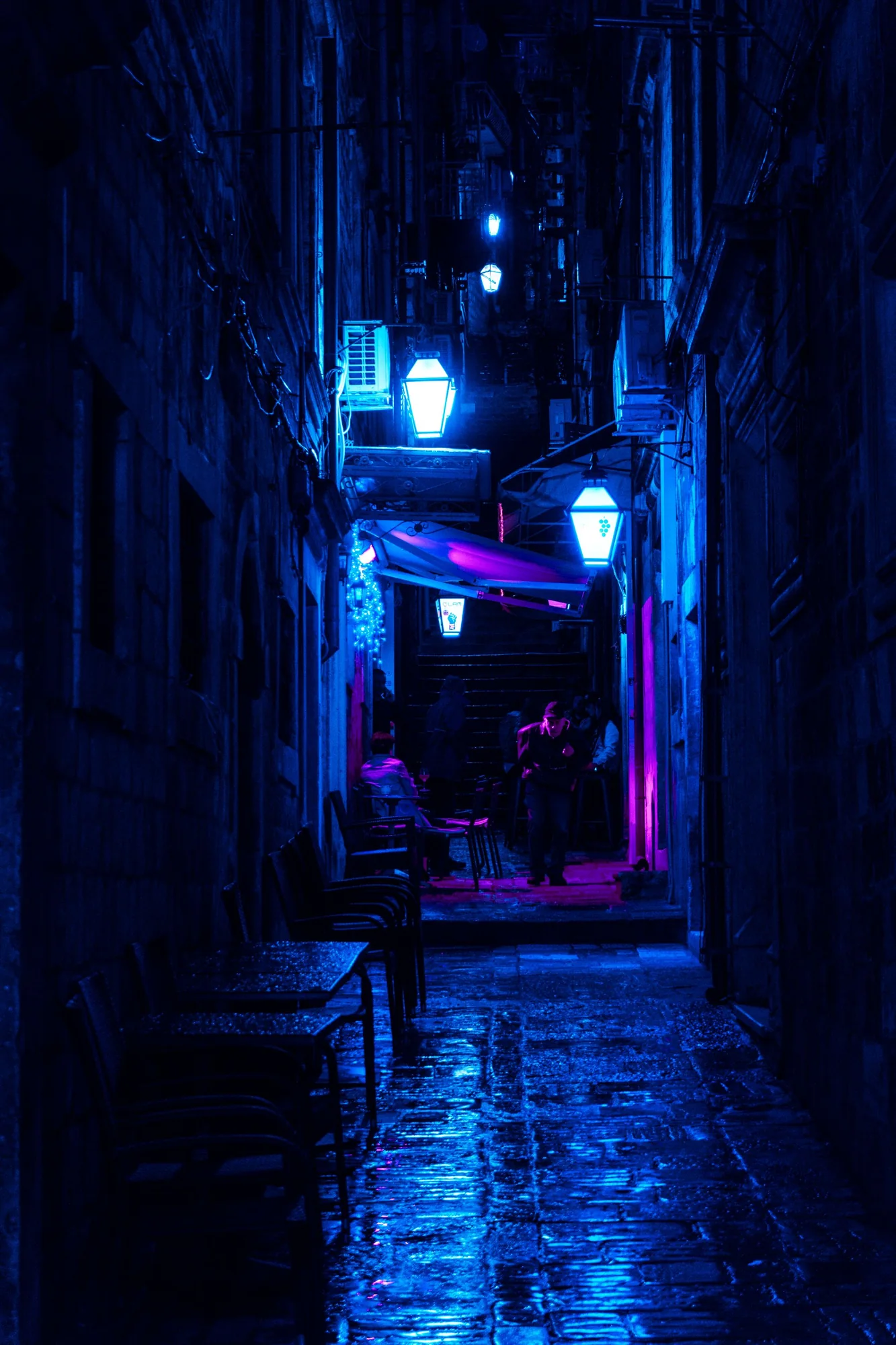 蓝色灯光映照着湿润的夜间巷道